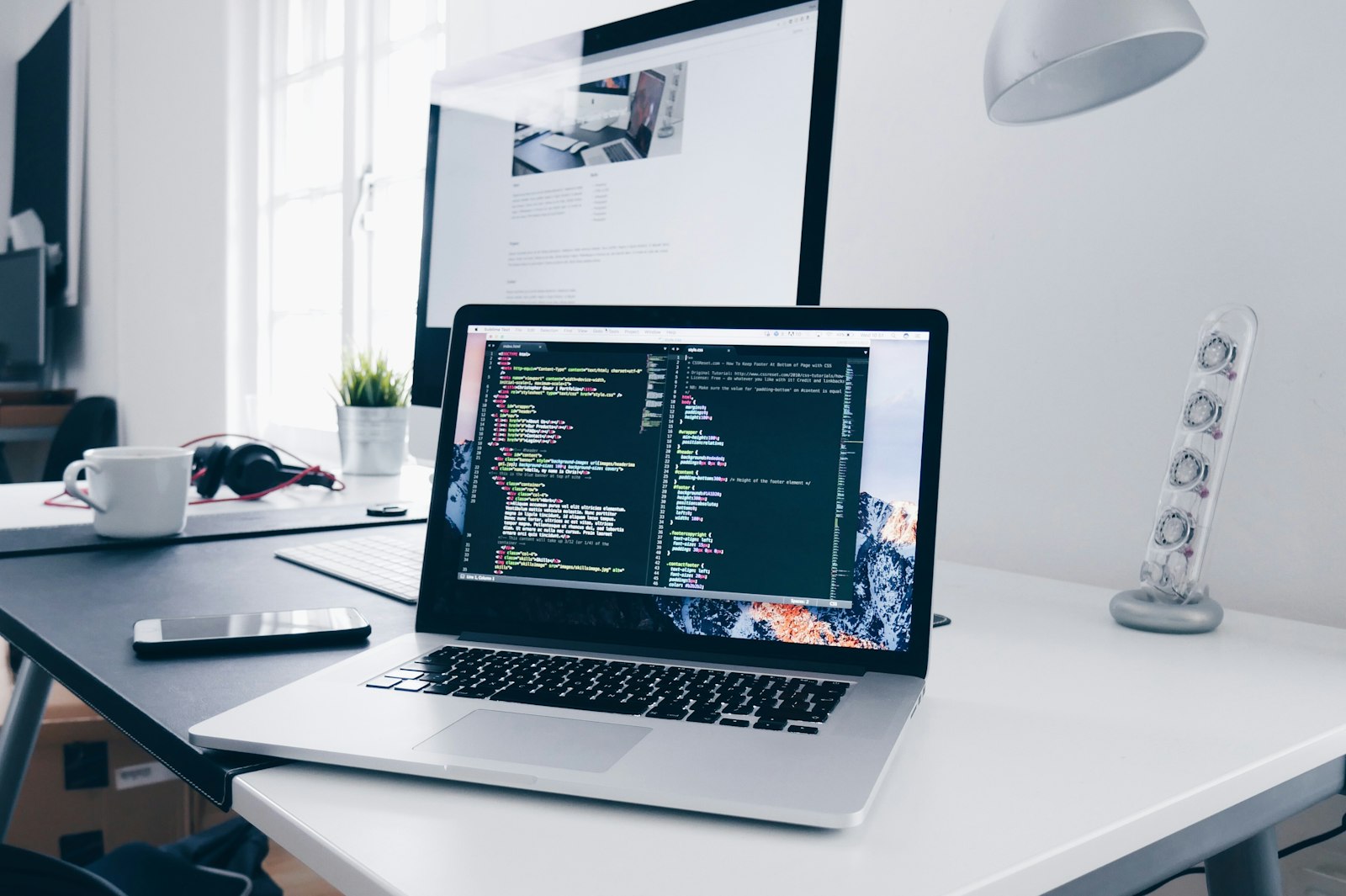 Developer writing code on a laptop at a bright desk